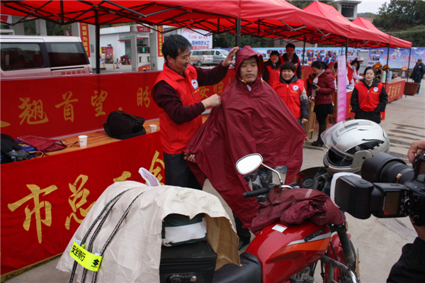 梧州市總工會的黨員義工們在市東出口春運服務(wù)站助力&ldquo;摩托大軍&rdquo;平安返鄉(xiāng)，幫助他們檢查車輛和行李，穿上雨衣。--黃賀峰攝.j